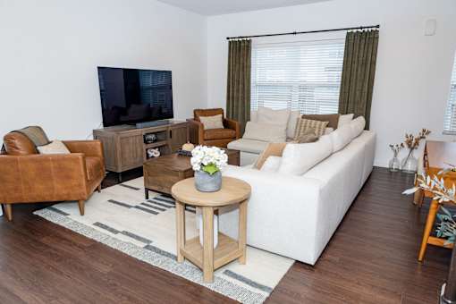 A living room with a white couch, a brown leather chair, a wooden coffee table, and a flat-screen TV. at Highland Village, Ross Township, Pittsburgh, PA 15229