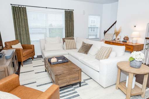 A living room with a white couch, brown armchair, and a wooden coffee table. at Highland Village, Ross Township, Pittsburgh, PA 15229
