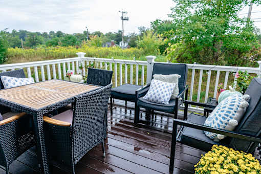 A wooden table and two chairs are on a porch. at Highland Village, Ross Township, Pittsburgh, PA 15229