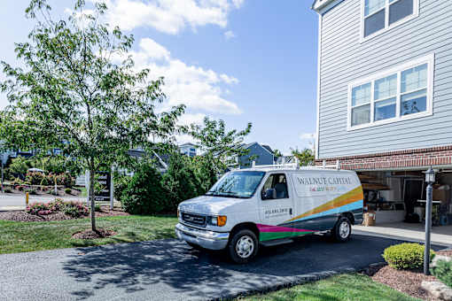 A white van with a rainbow stripe is parked in front of a house. at Highland Village, Ross Township, Pittsburgh, PA 15229