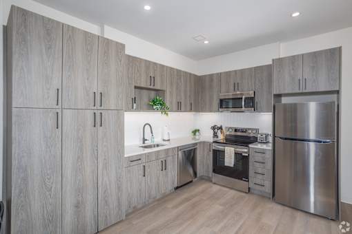 A modern kitchen with wooden cabinets and stainless steel appliances.at The Jones Tower at the Collective, Pittsburgh, PA 15203