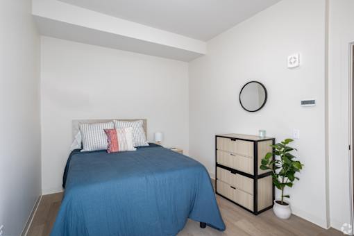 A bedroom with a blue bedspread and a white wall.at The Jones Tower at the Collective, Pittsburgh, PA 15203