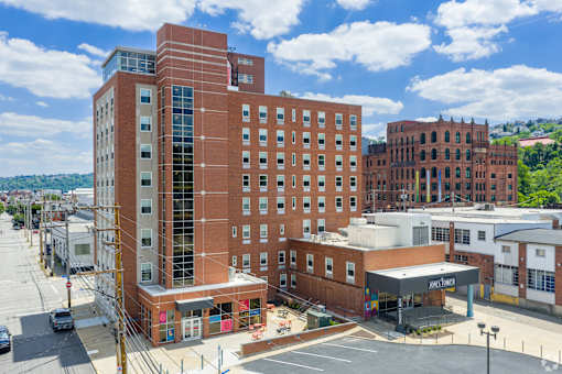 A large red brick building with a parking lot in front.at The Jones Tower at the Collective, Pittsburgh, PA 15203