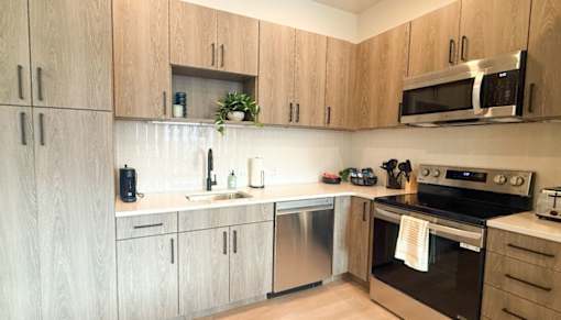 A kitchen with wooden cabinets and stainless steel appliances.at The Jones Tower at the Collective, Pittsburgh, PA 15203