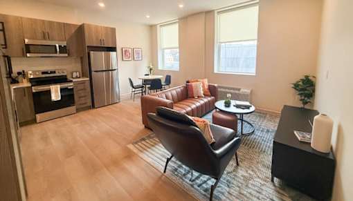 A modern kitchen and living room with a brown leather couch and a wooden floor.at The Jones Tower at the Collective, Pittsburgh, PA 15203