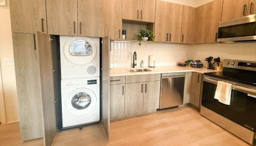 A modern kitchen with a washing machine built into the cabinetry.at The Jones Tower at the Collective, Pittsburgh, PA 15203