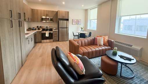 A modern living room with a kitchen in the background.at The Jones Tower at the Collective, Pittsburgh, PA 15203