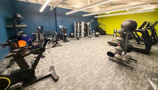 A gym with a variety of equipment including a rowing machine, a leg press machine, and a weight bench.at The Jones Tower at the Collective, Pittsburgh, PA 15203
