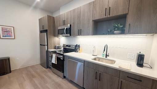 A kitchen with wooden cabinets and stainless steel appliances.at The Jones Tower at the Collective, Pittsburgh, PA 15203
