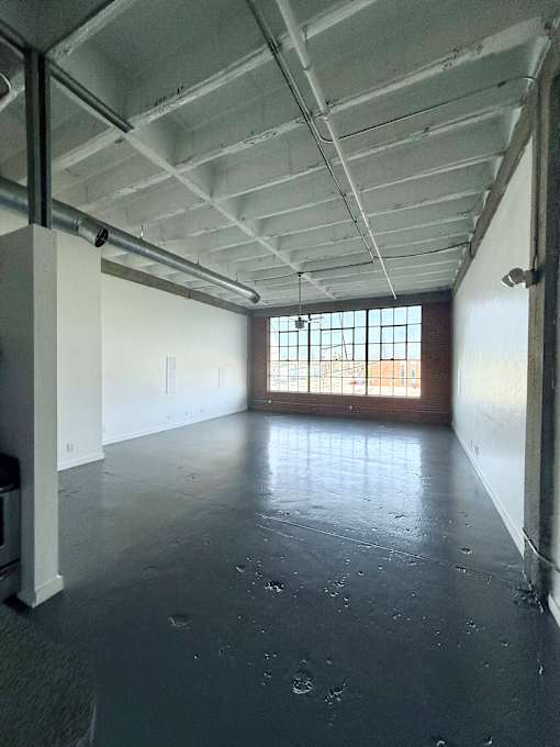 A large empty room with a window and a door.