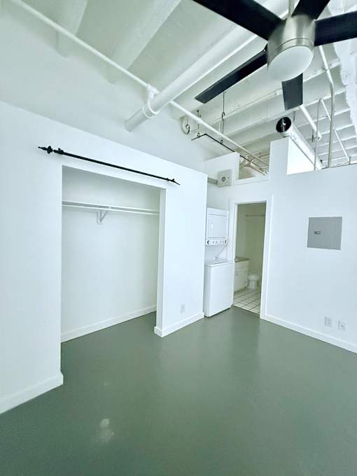 A white room with a black ceiling fan and a white door.
