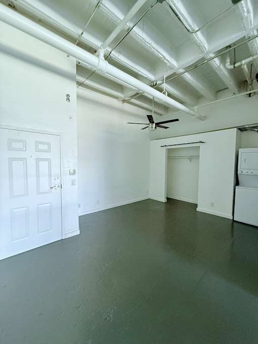 A room with a ceiling fan and white walls.