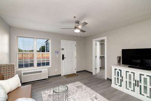 an open living room with a large window and a ceiling fan