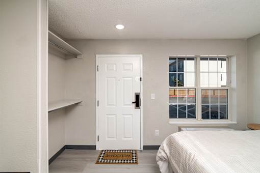 a bedroom with a bed and a white door and a window