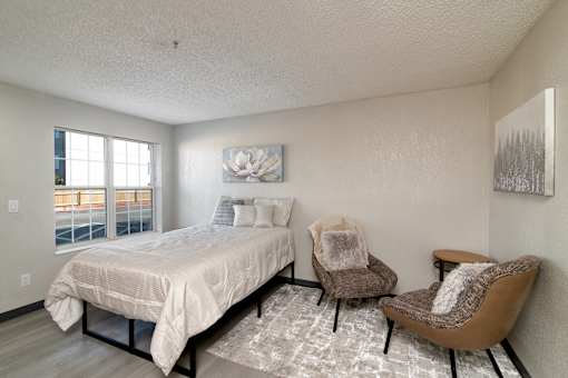 a bedroom with a bed and two chairs and a window