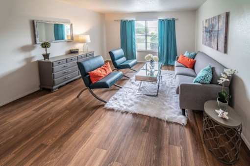 A living room with a grey couch, a black chair, and a wooden floor.