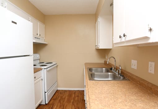 A kitchen with a white refrigerator, stove, and sink.