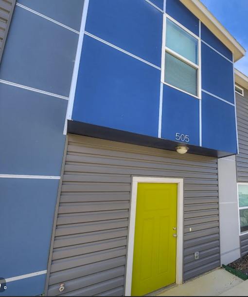A blue building with a yellow door and a window.