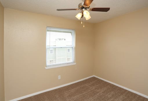 A room with a ceiling fan and a window.