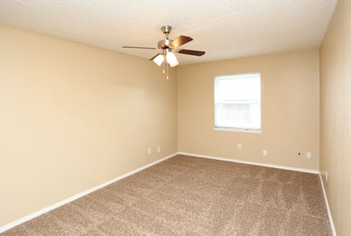 A room with a ceiling fan and carpeted floor.