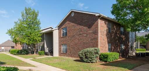 A brick house with a green tree in front.