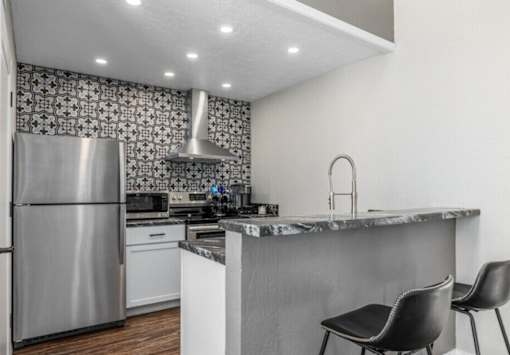 A modern kitchen with a marble countertop and a black chair.