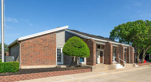 A small brick building with a tree in front.