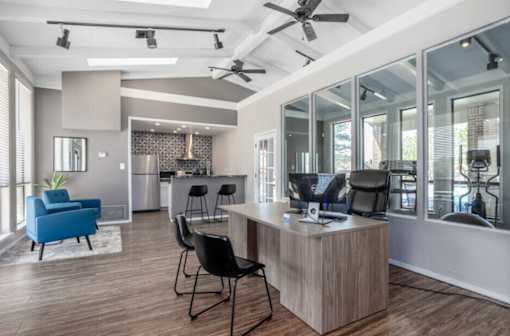 A modern office space with a wooden desk and blue chairs.