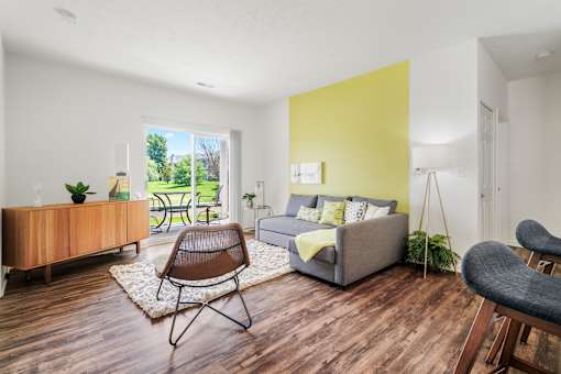 A living room with a grey couch, a brown chair, and a yellow accent wall.