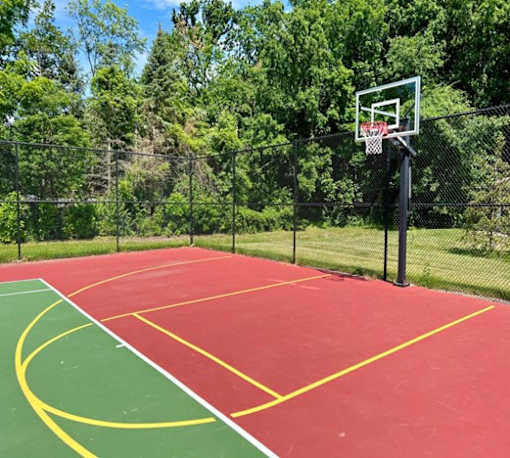 A basketball court with a red surface and yellow lines.