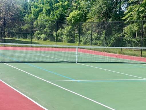 A tennis court with a net and green and red markings.