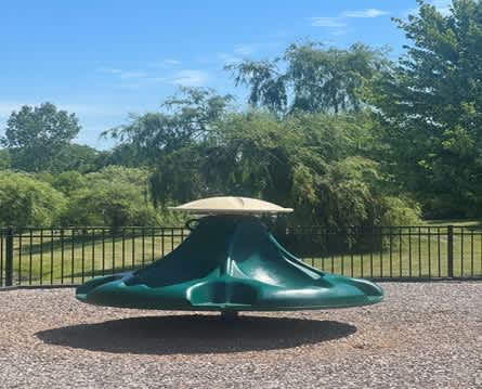 A green playground slide with a white top in the middle of a park.
