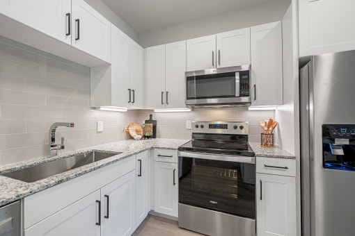 a kitchen with white cabinets and stainless steel appliances at Alta Denton Station, Denton, Texas