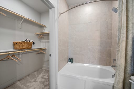 a bathroom with beige tiles and a white bathtub at Alta Denton Station, Denton, Texas