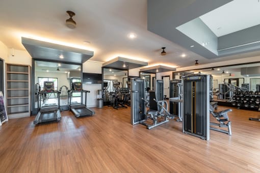Gym with Cardio Equipment and Weights on a Wooden Floor at AVILA Apartments, Florida