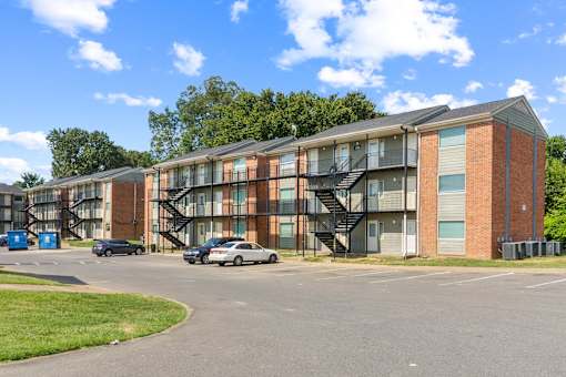 A large apartment complex with a parking lot in front.