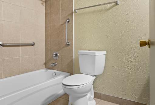 A white toilet sits next to a bathtub in a bathroom.