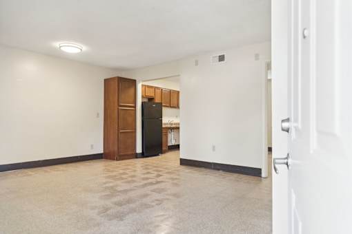 A kitchen area with a black fridge and wooden cabinets.