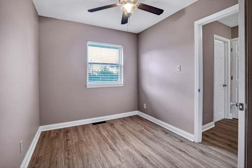 A room with a ceiling fan and a window with blinds.