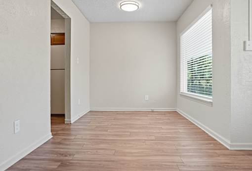 A room with wooden flooring and a window with blinds.