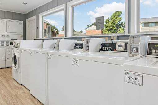 A row of white washing machines are lined up in a laundry room.