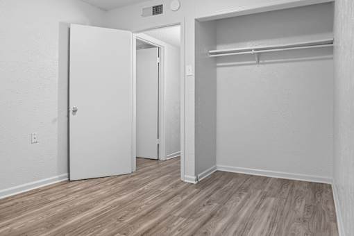 A room with a white door and a white closet with a shelf.