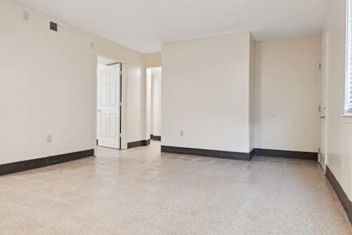 A large empty room with a door on the left and a window on the right.