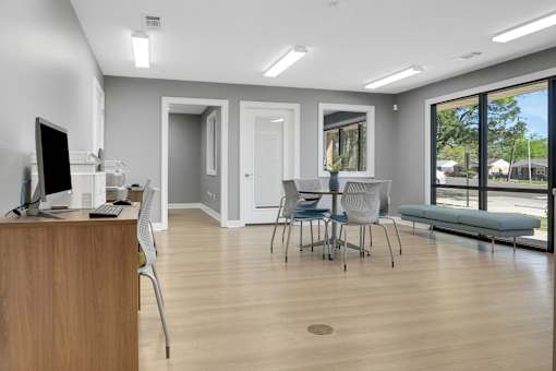 A room with a desk, chairs, and a window overlooking a street.