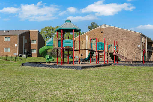 A playground with a green slide and red and green play equipment.