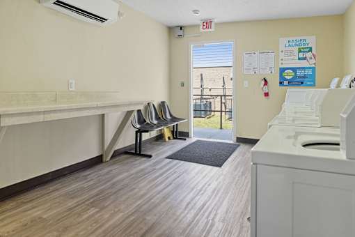 A laundry room with a washer and dryer, a bench, and a window.