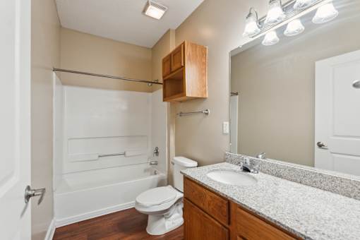 A bathroom with a toilet, sink, and mirror.