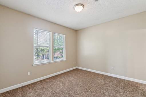 A room with a carpeted floor and a window.