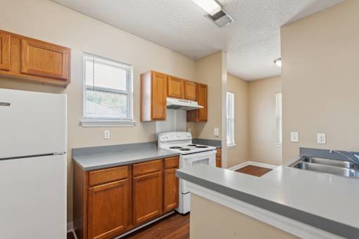 A kitchen with white appliances and wooden cabinets.