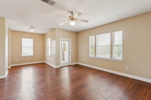 Empty room with wood flooring and a ceiling fan.